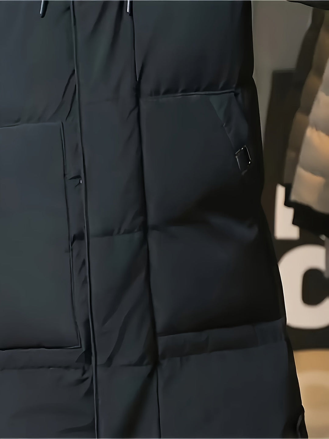 Daan zwarte jas zakdetail met drukknoop dichtbij