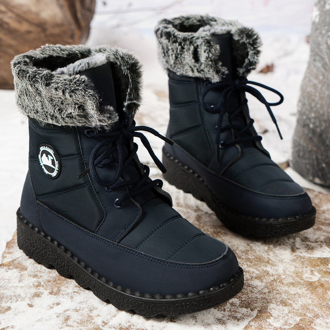 Donkerblauwe snowboots met bontkraag op besneeuwde rots