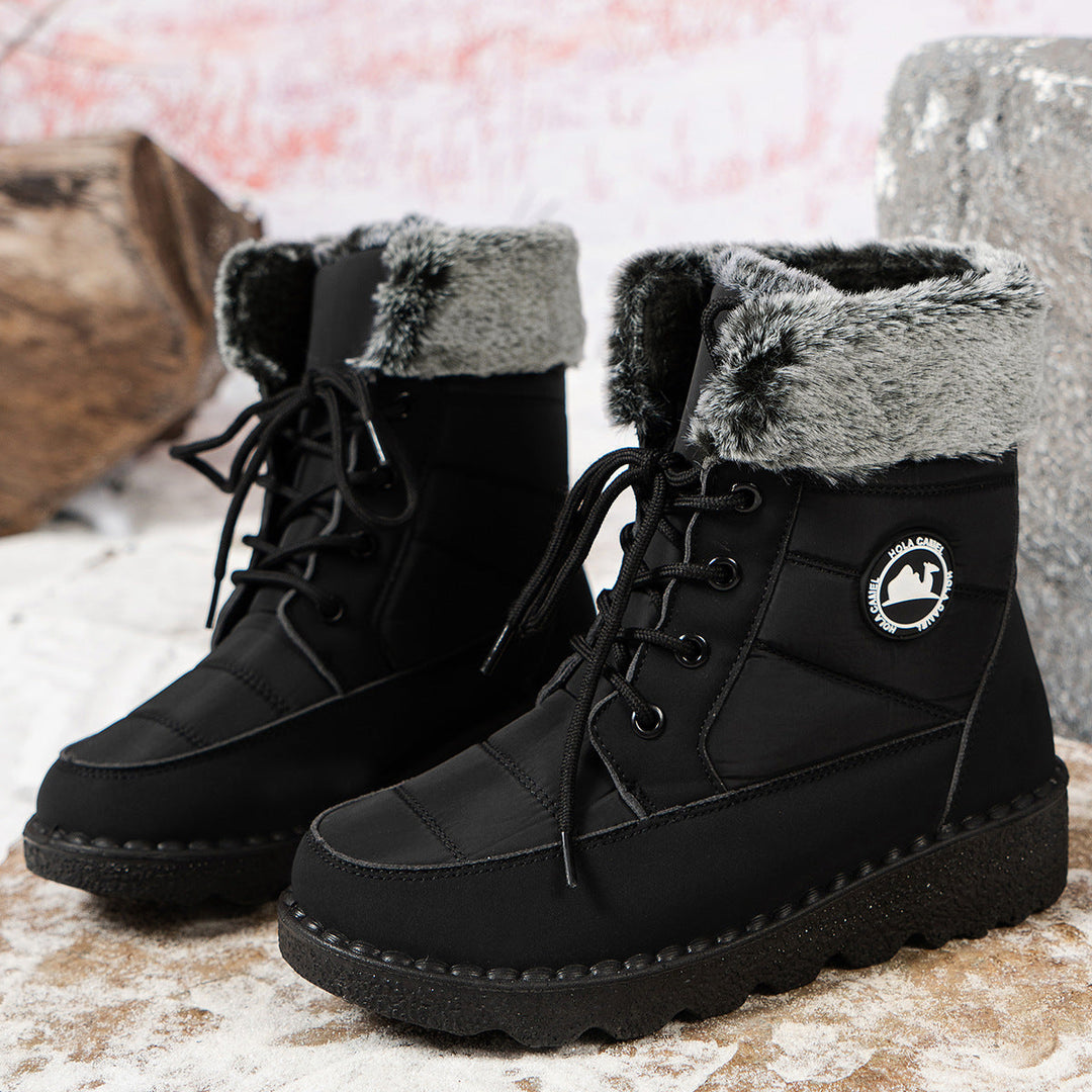 Zwarte snowboots met bontkraag en logo op besneeuwde rots