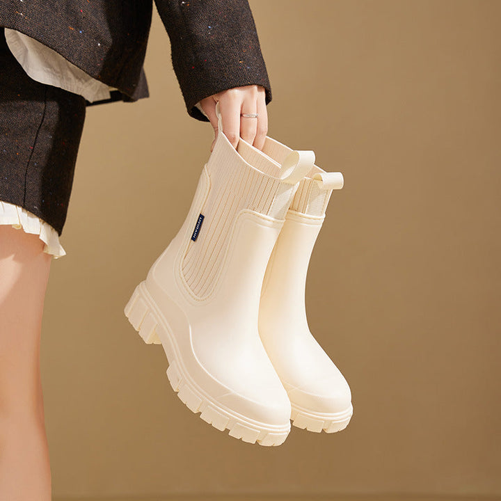 Iris Chelsea regenlaarzen in beige, model houdt laarzen vast