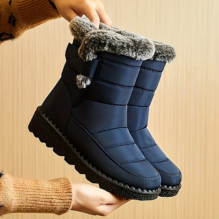 Sanne blauwe gevoerde enkelhoge snowboots met bontrand, vasthouden in handen
