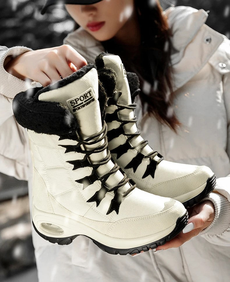 Sanne gevoerde snowboots in lichte kleur vastgehouden door model in sneeuw