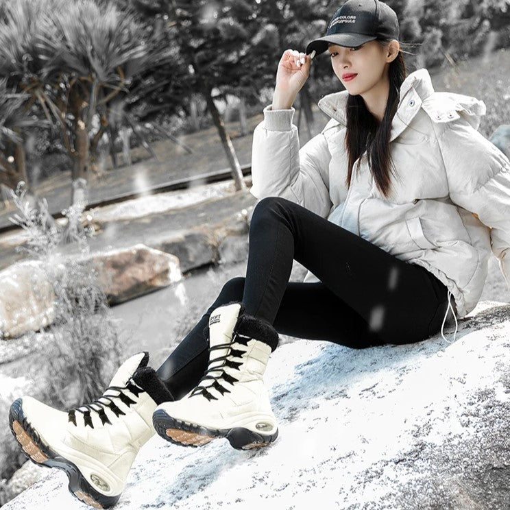 Model zittend op rots met lichtgekleurde snowboots aan