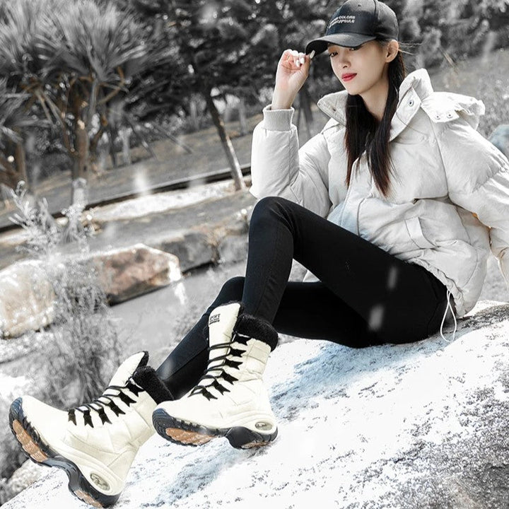 Model zittend op rots met lichtgekleurde snowboots aan