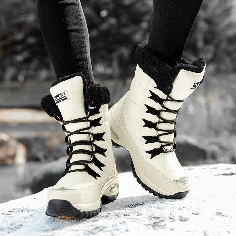 Achteraanzicht van lichtgekleurde snowboots met bontkraag op besneeuwde rots