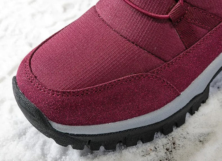 Close-up van de neus van de bordeauxrode snowboot in de sneeuw